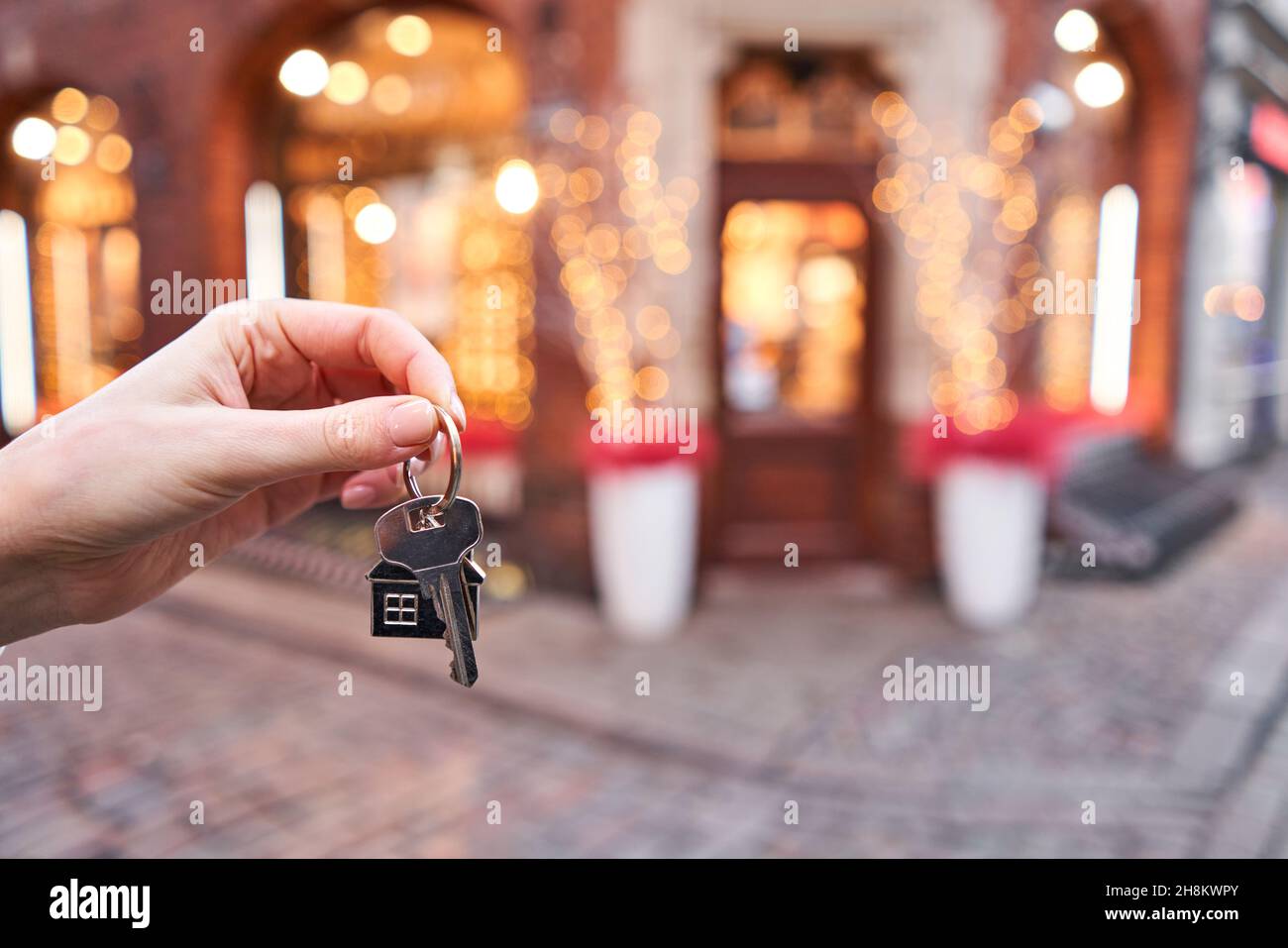 Mortgage or rent concept. Woman holding key with wooden house keychain . Real estate, hypothec, moving home or renting property. Christmas mood in blu Stock Photo