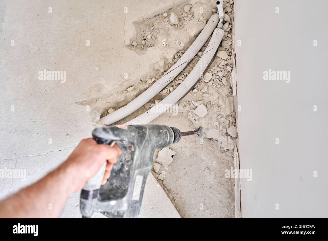 connection heating pipes to white Radiator in a new apartment under construction. Work As A Plumber, mounting water heating radiator on the white wall Stock Photo