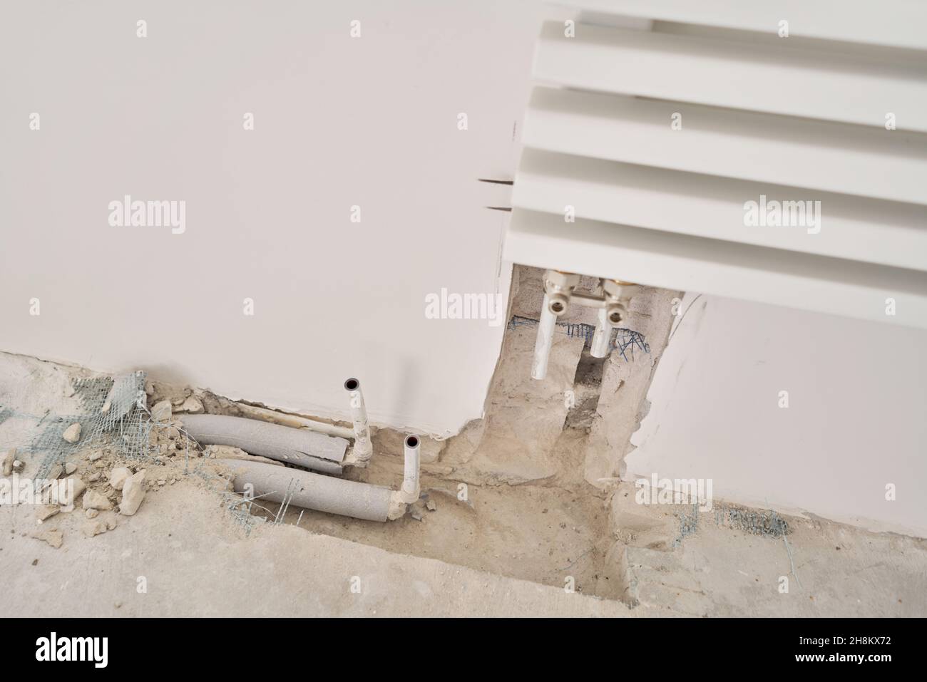 connection heating pipes to white Radiator in a new apartment under construction. Work As A Plumber, mounting water heating radiator on the white wall Stock Photo