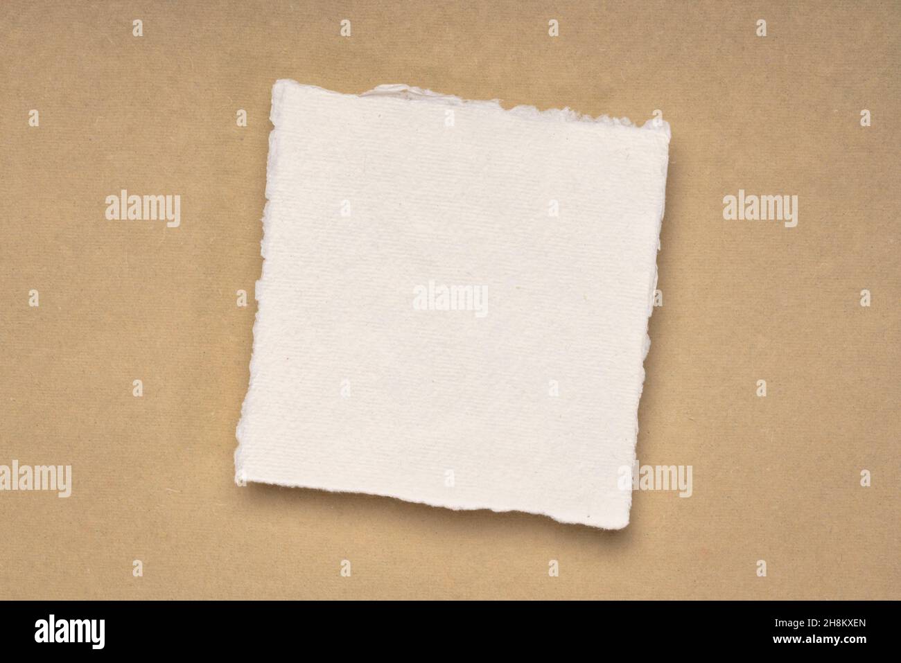 small square sheet of blank white Khadi paper against beige rag