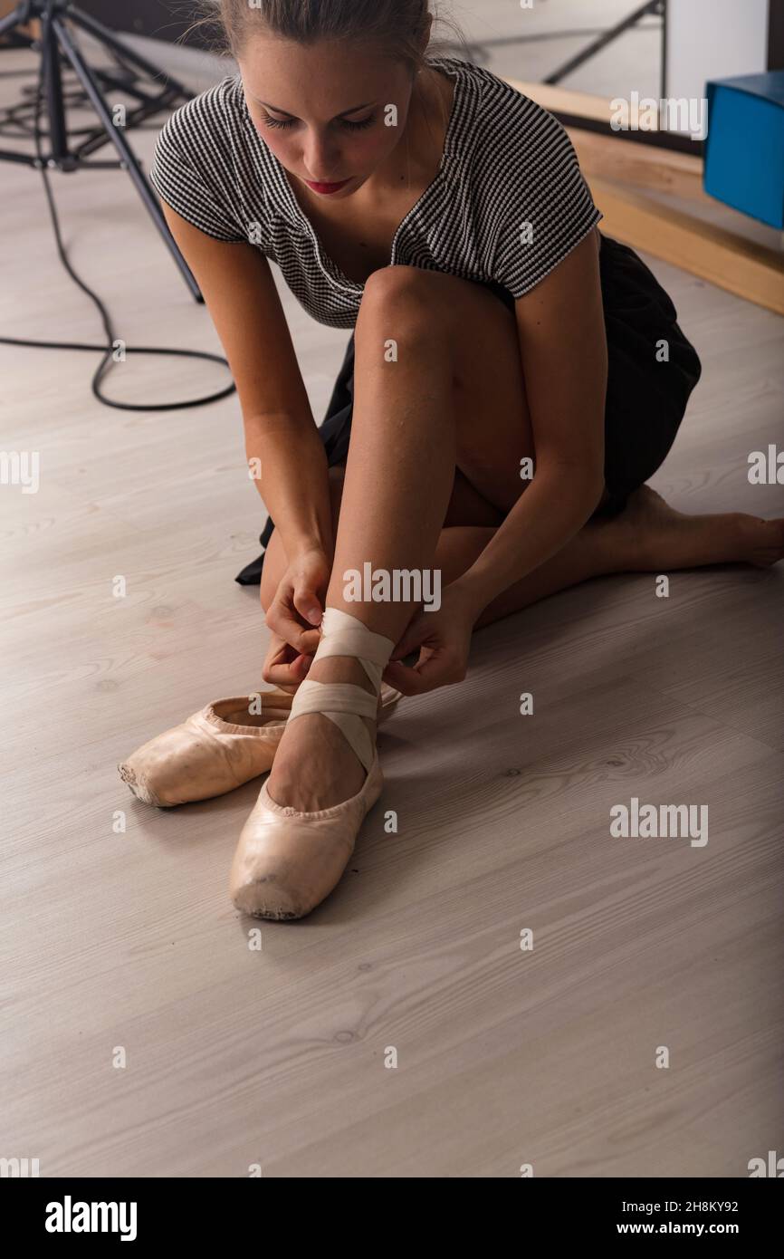 Ballerina busy tying her ballerina shoes at the height of her beautiful