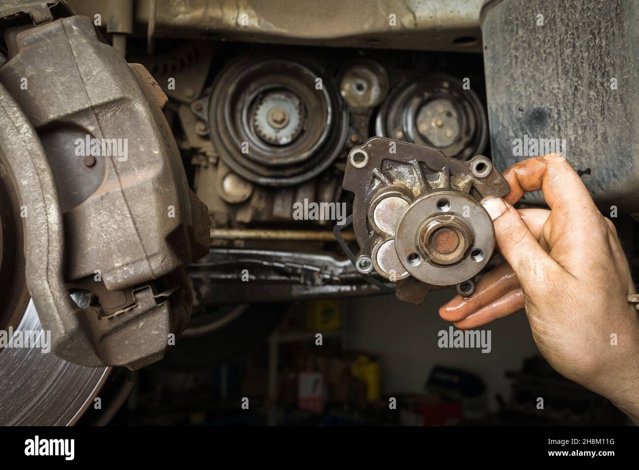 The car mechanic holds in his hand an old removed car engine water pump Stock Photo