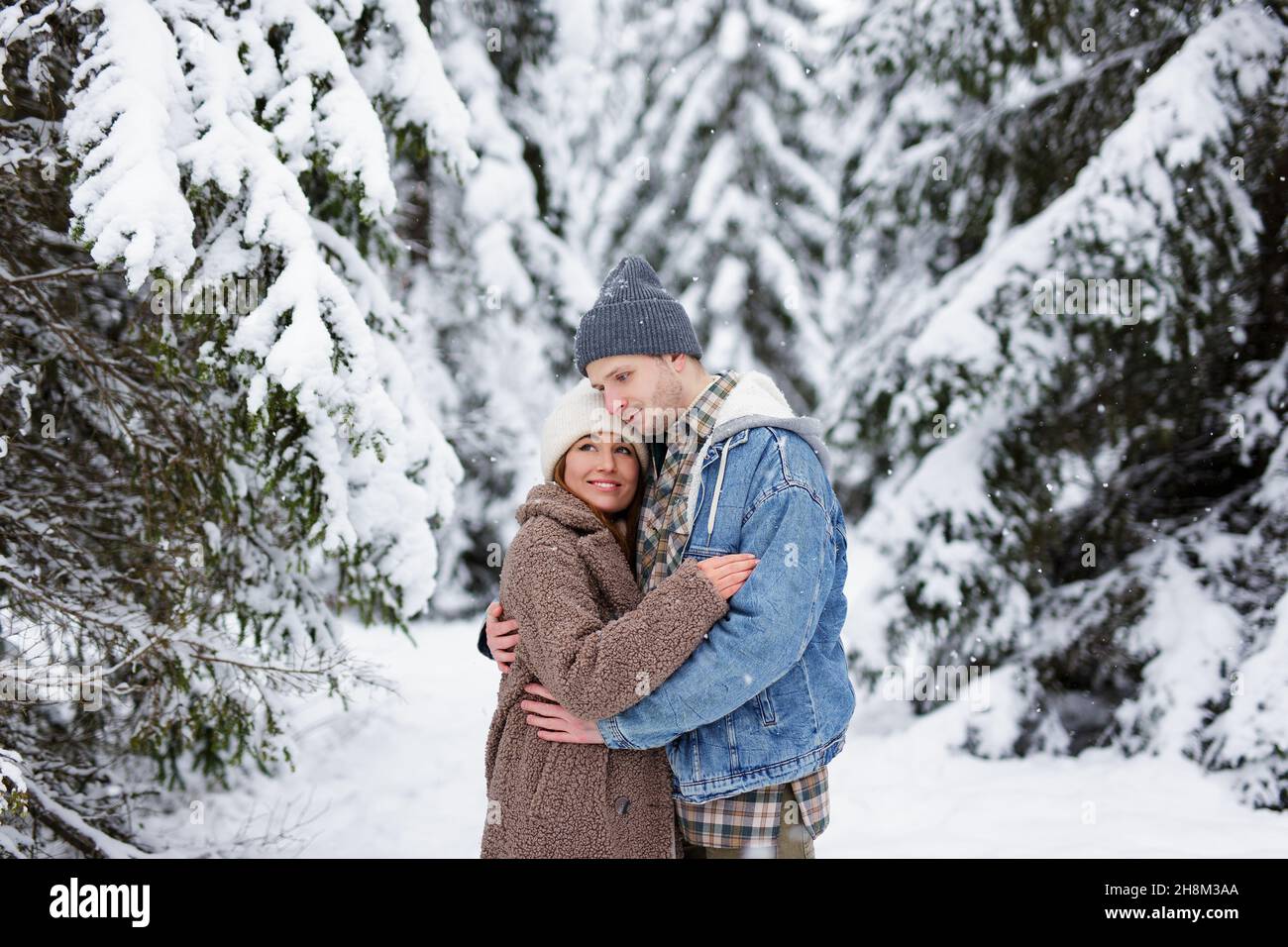 portrait of cute couple in love embracing in winter forest or park ...