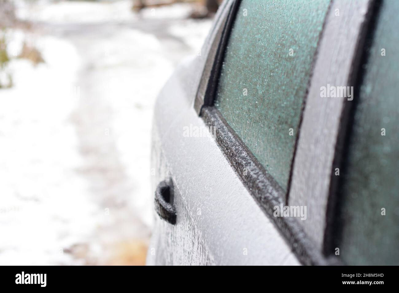 A closeup of a frozen car door, car window covered with ice