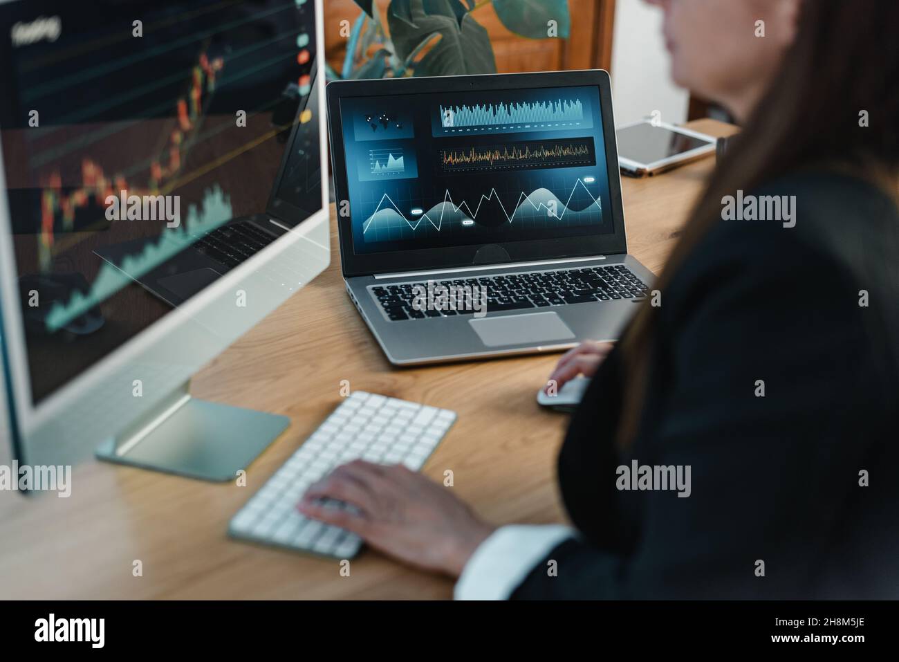 Crop trader at table with laptop and computer screen Stock Photo