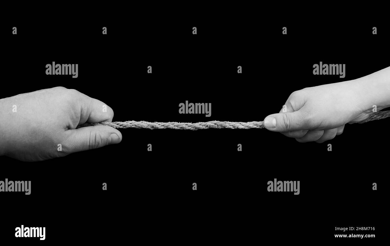 Hand of man and woman tug the rope isolated on black background ...