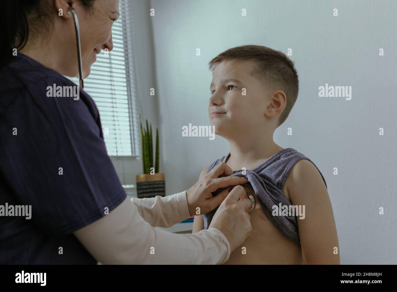 Child Having Pediatric Checkup at Doctor Office. Female Doctor Examining 7 Year Old Boy with Stethoscope at Medical Clinic. Stock Photo