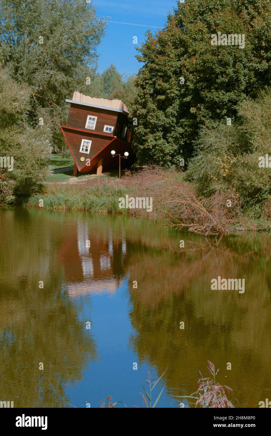 Picturesque fairy view. A house turned upside down, a fallen tree and their reflections in the water surface of the river. Stock Photo