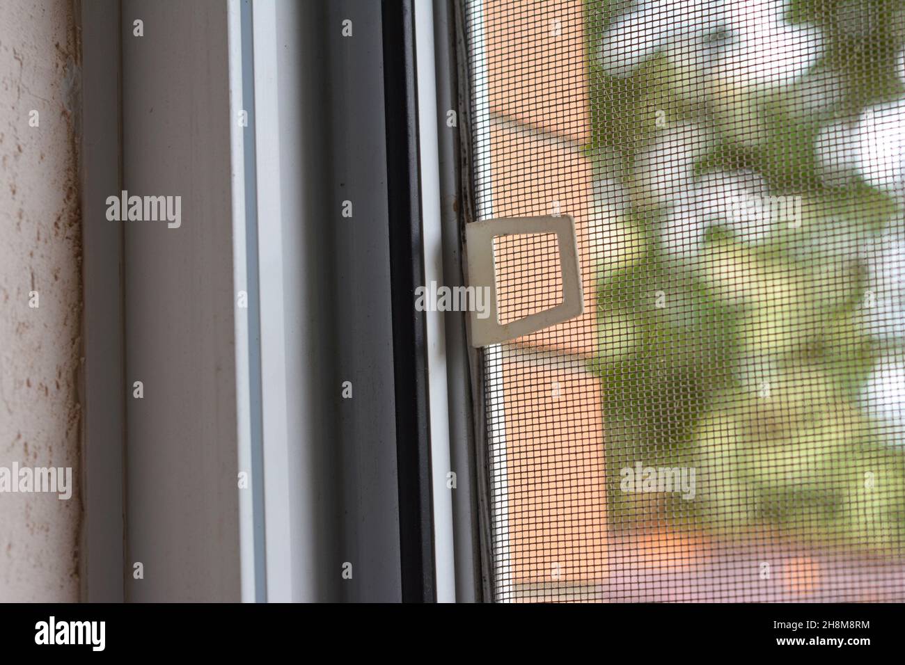 A closeup of a mosquito screen installed on a plastic window. House