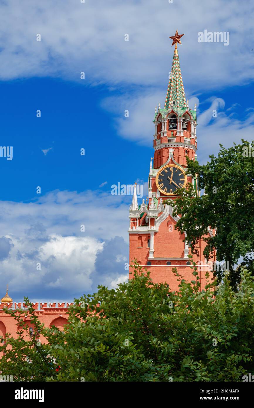 Spasskaya Tower of the Moscow Kremlin behind the green foliage of trees Stock Photo