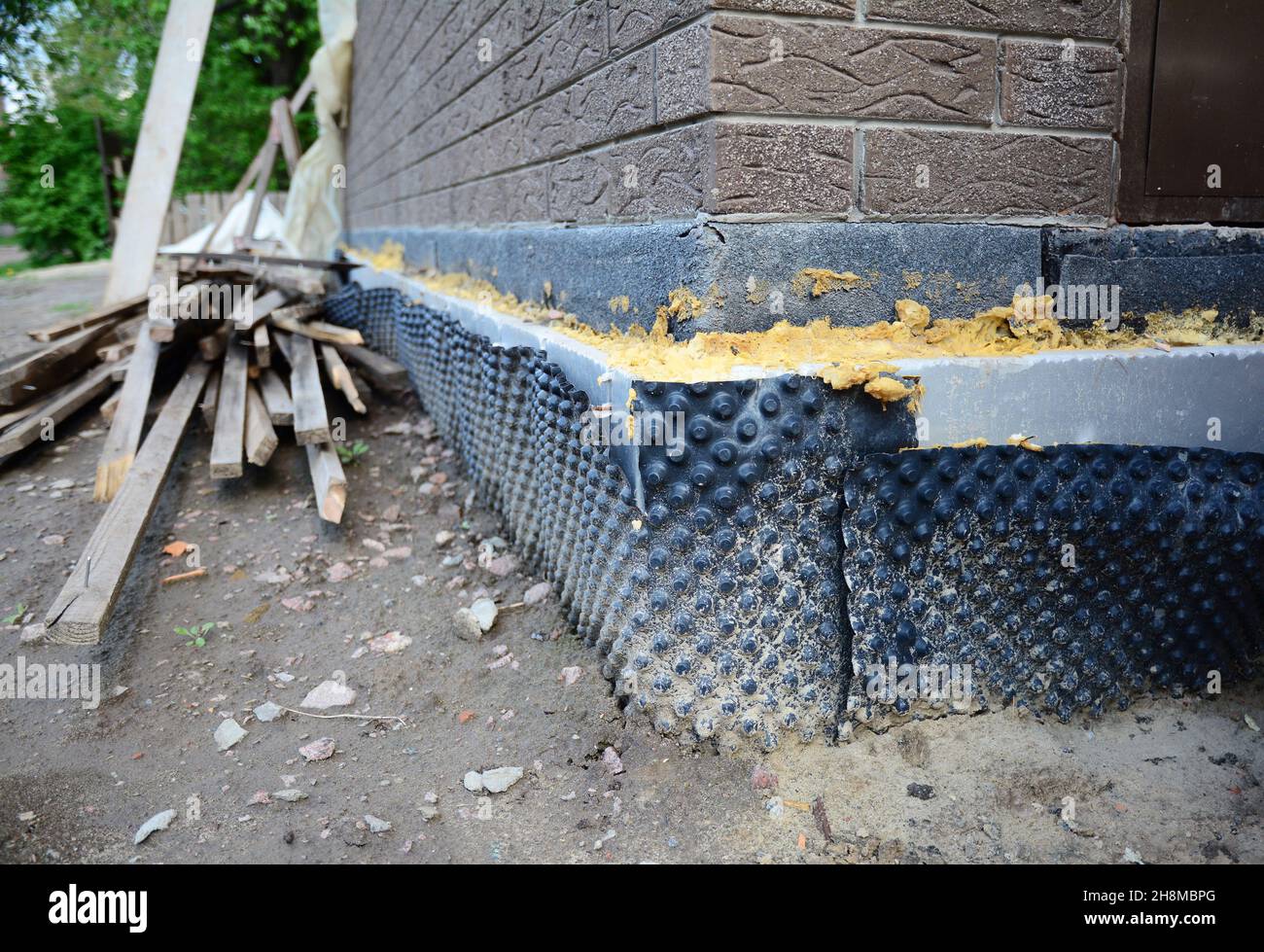 House foundation insulation. Foundation corner insulated with sprayed tar, extruded polystyrene