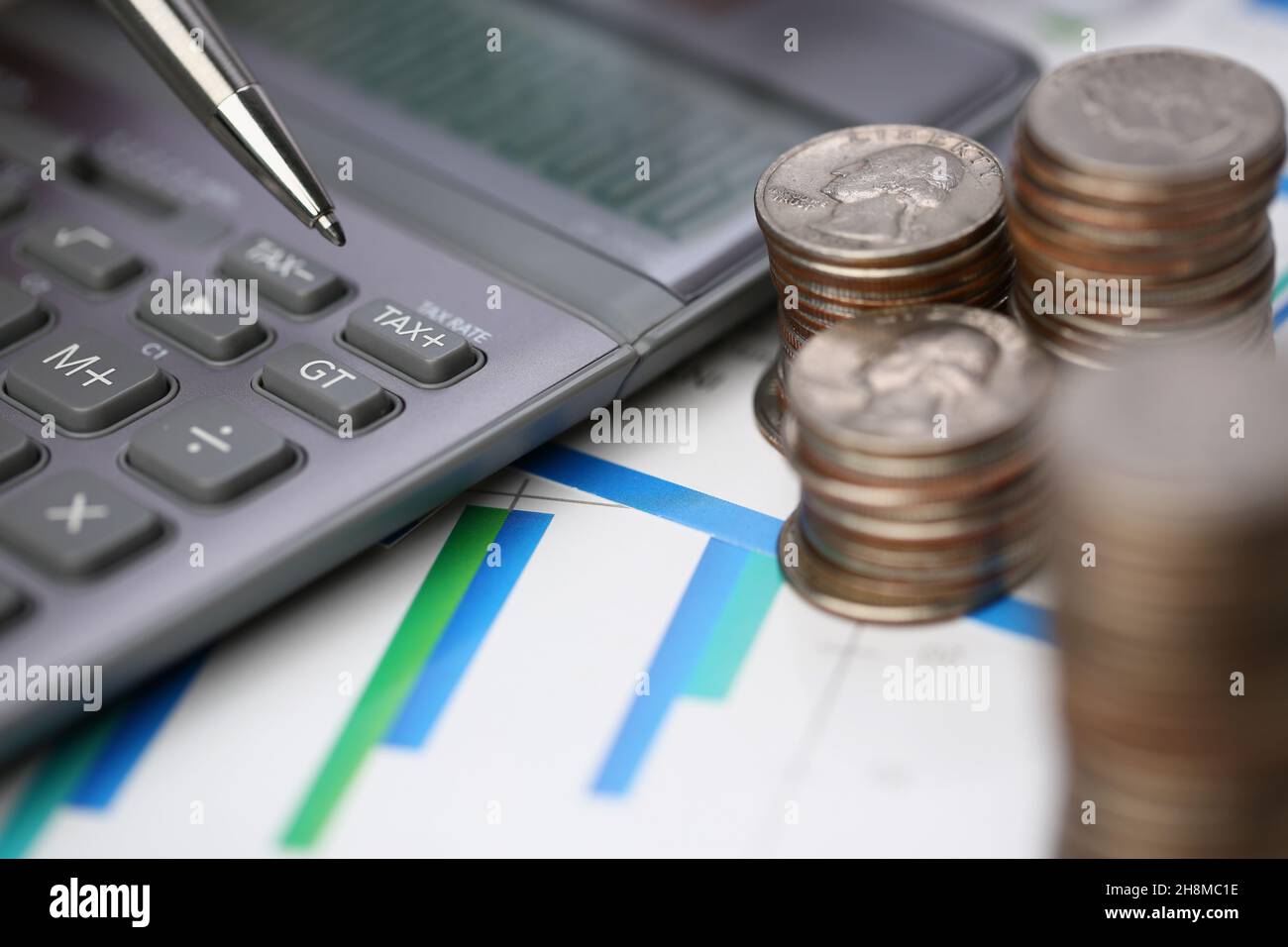 Closeup of silver calculator with keyboard lying on desk cash quarter