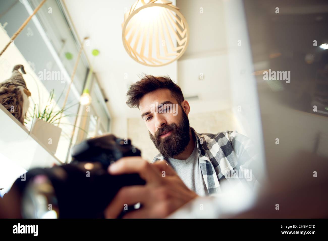 Hipster young man holding a DSLR camera and checking settings Stock