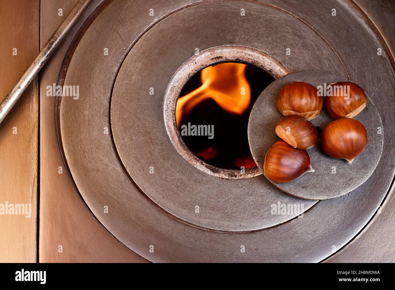 Overhead photograph of some chestnuts over a wood stove fire.The photo has a vintage style and is taken in horizontal format. Stock Photo