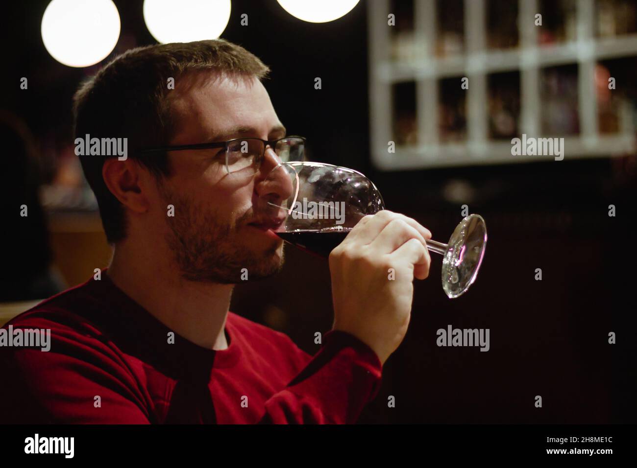 Young man in a restaurant drinking red wine from a glass Stock Photo