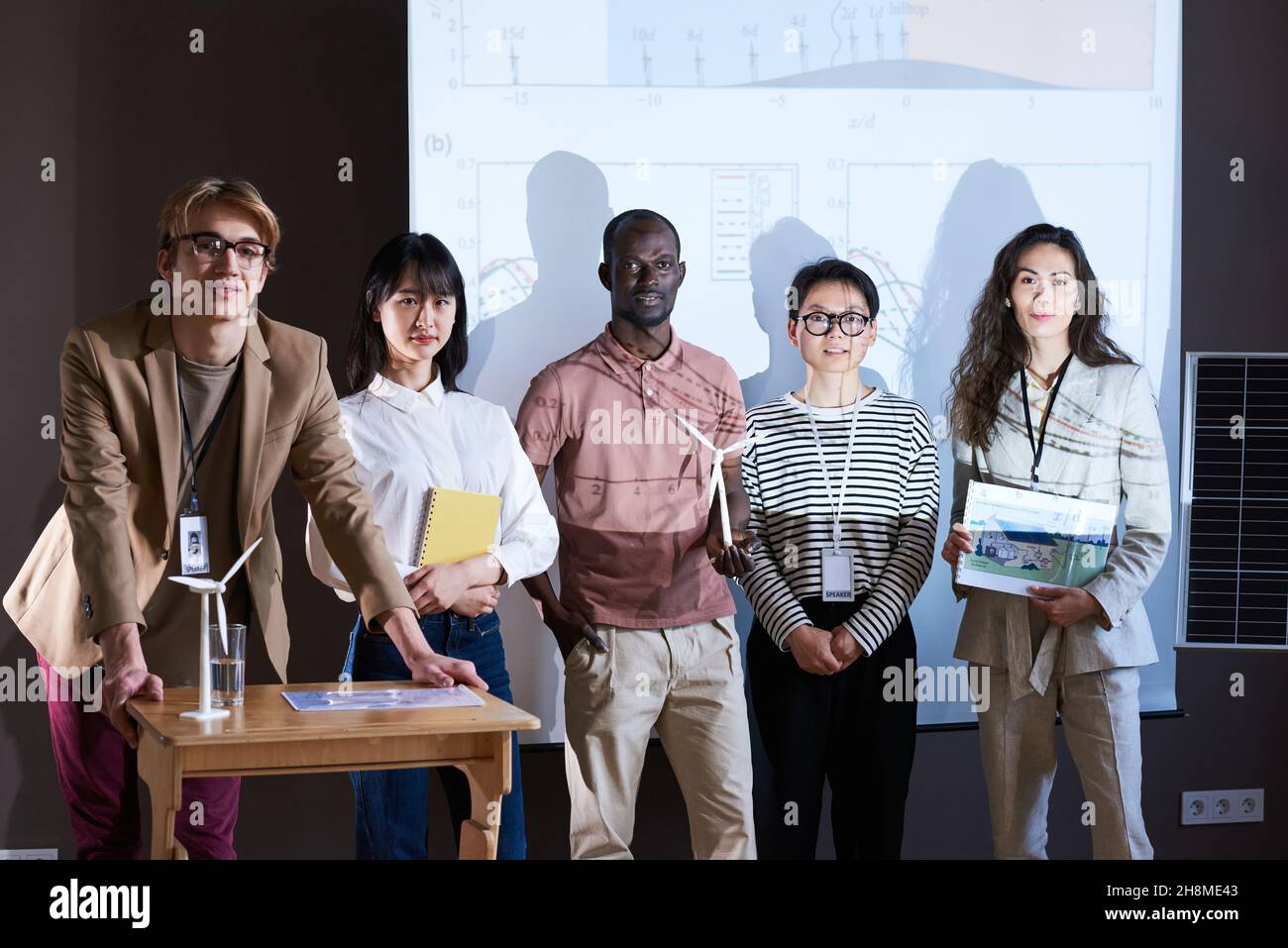 Portrait of group of architects smiling at camera while standing against the big monitor at conference Stock Photo