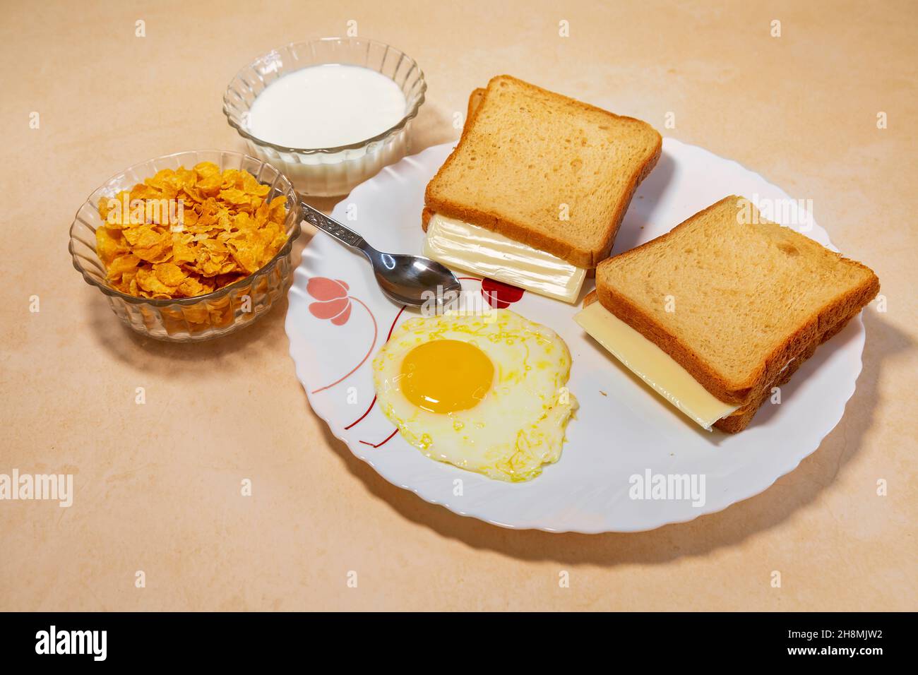 Healthy Indian breakfast of brown bread with cheese slice and poached egg served with corn flakes and fruit juice Stock Photo