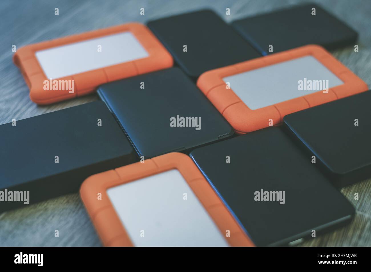 Many portable hard drives on the wooden floor. Mosaic of usb storage devices. External computer equipment. Cloud technology, online disk, remote backu Stock Photo