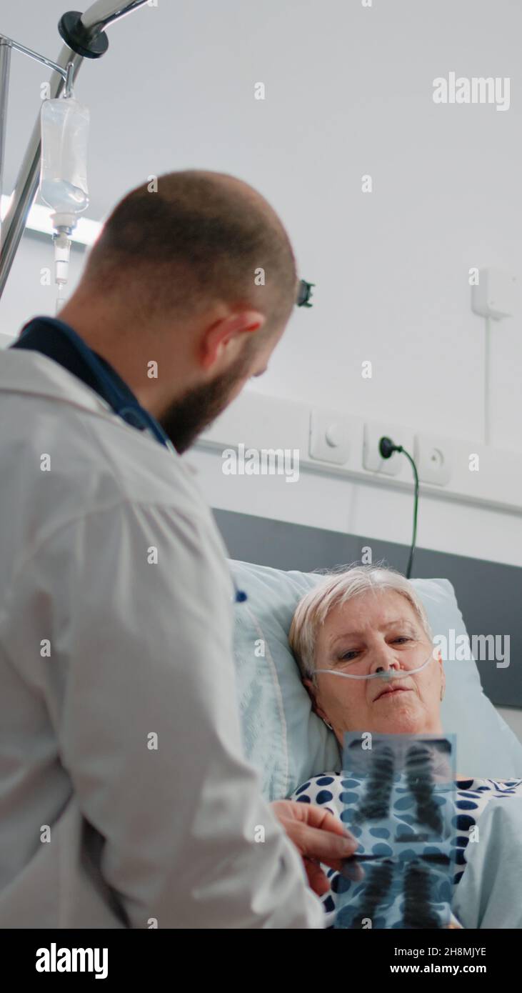 Doctor showing diagnosis of radiography to patient with illness laying ...