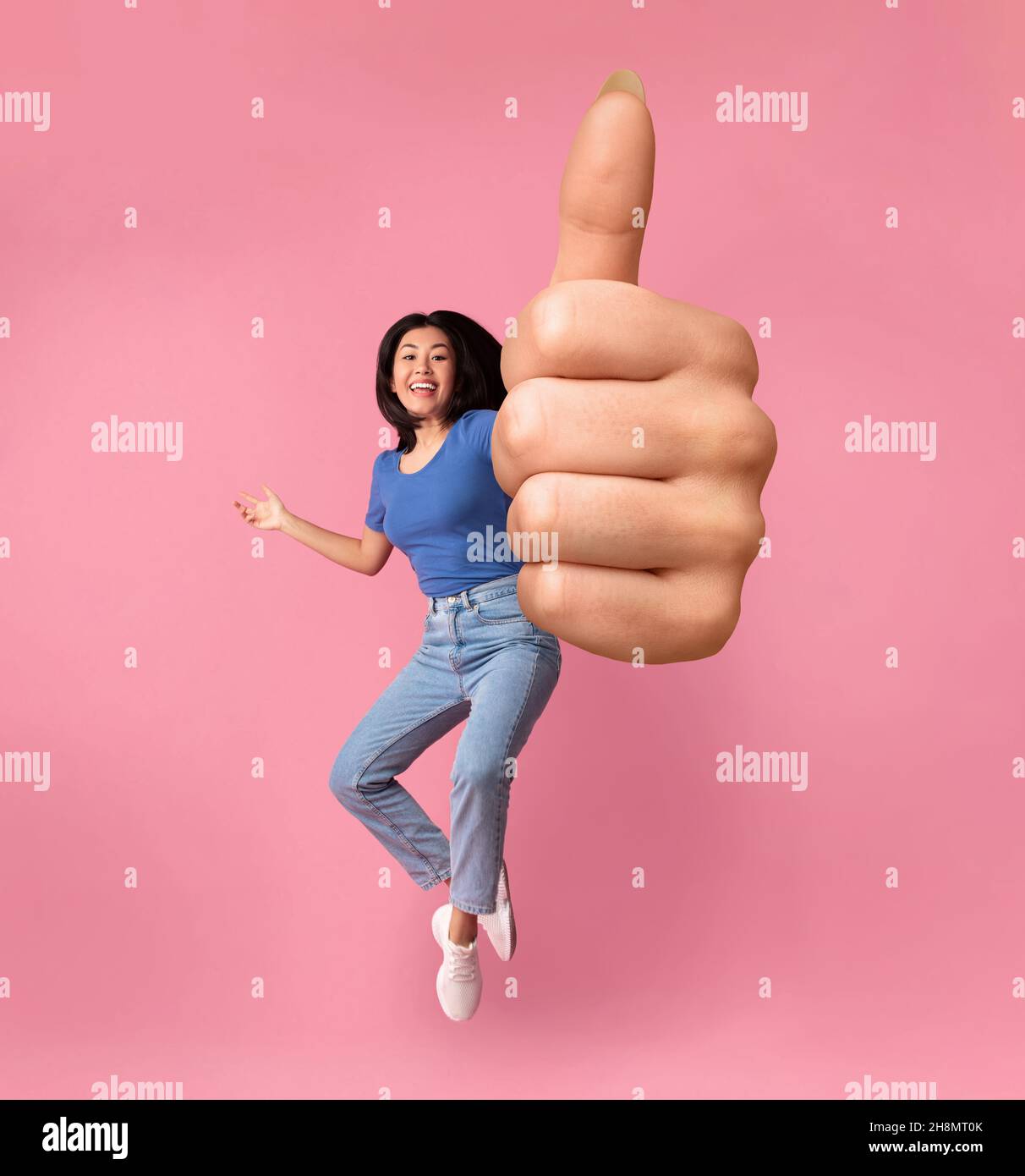 Cheerful Asian Girl Jumping In Air And Showing Thumb Up Stock Photo - Alamy