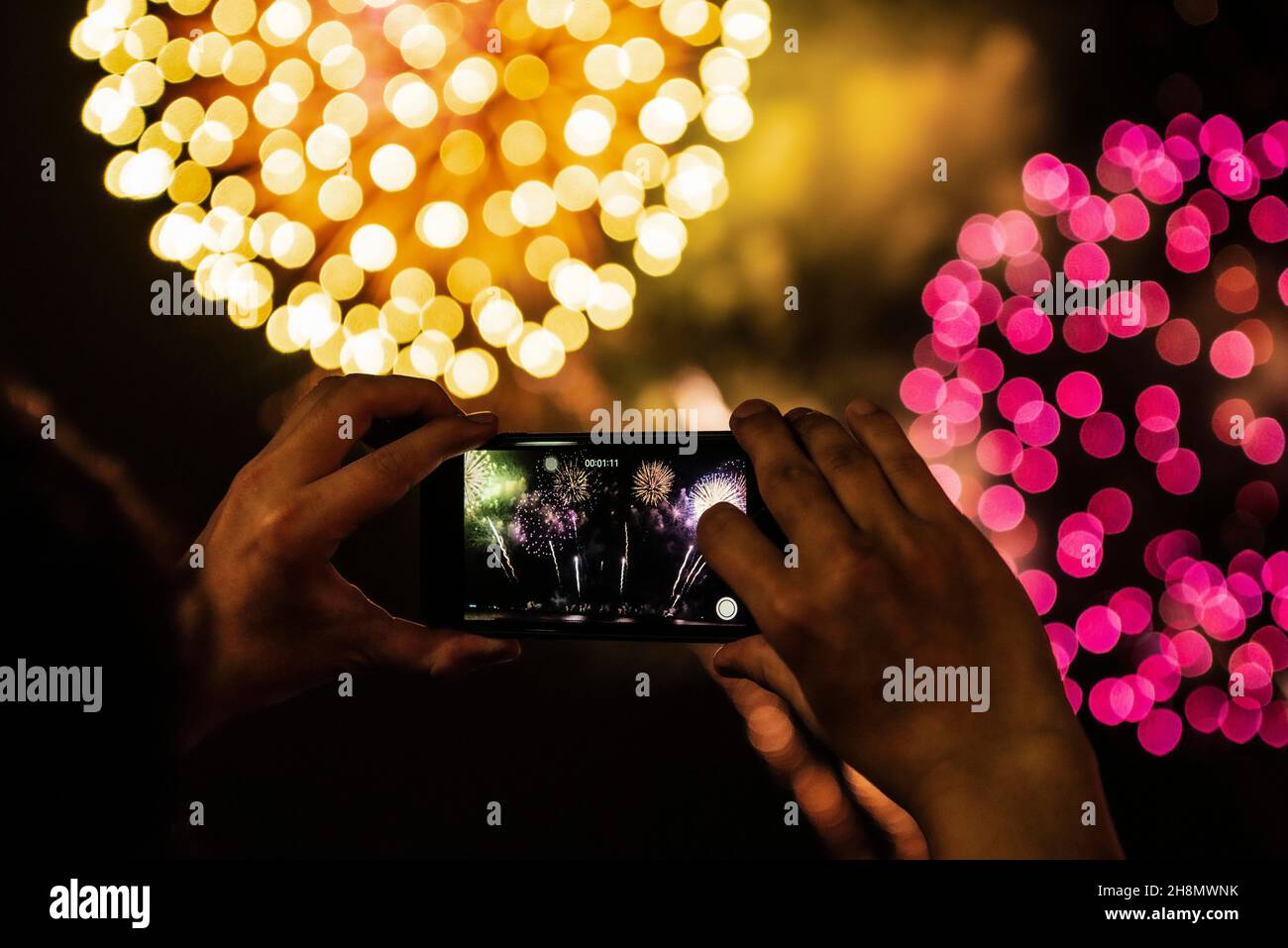 Hand holding mobile phone, smartphone filming fireworks, New Year's Eve Stock Photo