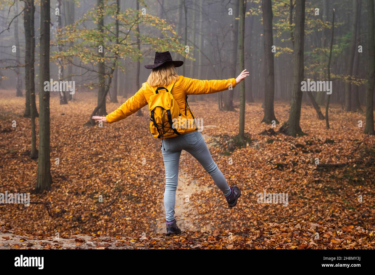 Hiking in autumn forest. Woman tourist with cowboy hat and backpack ...