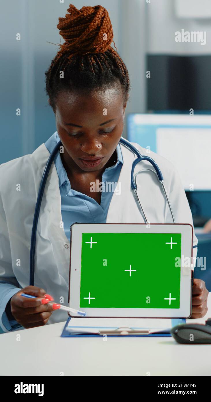Woman doctor pointing at tablet with horizontal green screen ...