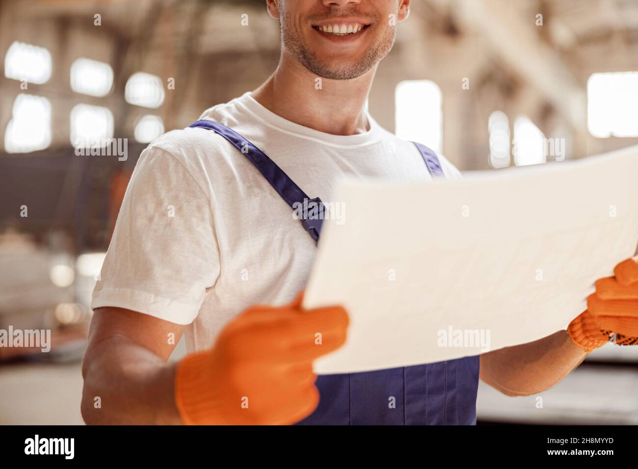 Joyful builder with architectural plan working at construction site Stock Photo