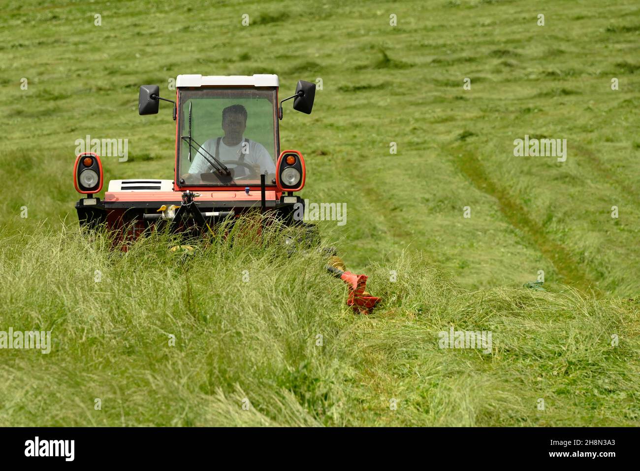 Farmer cutting grass with a tractor Stock Photo Alamy