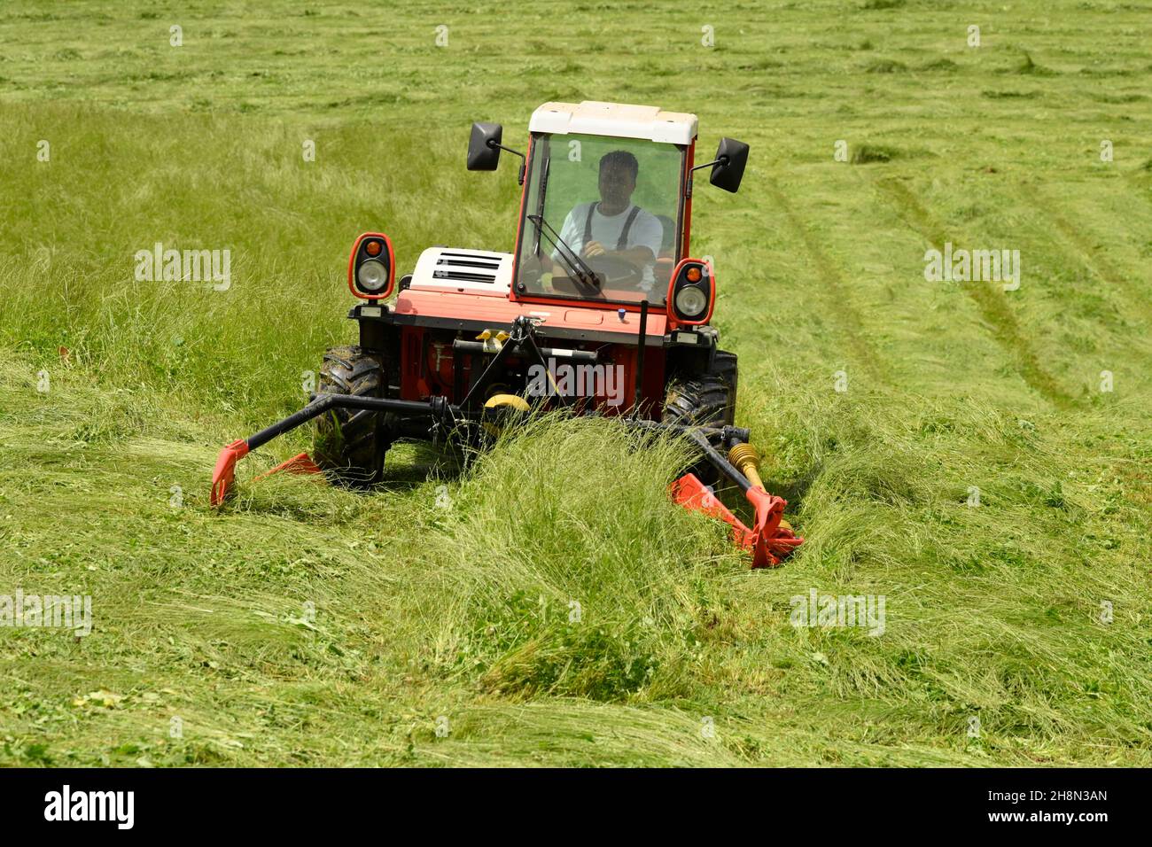 Farmer cutting grass with a tractor Stock Photo