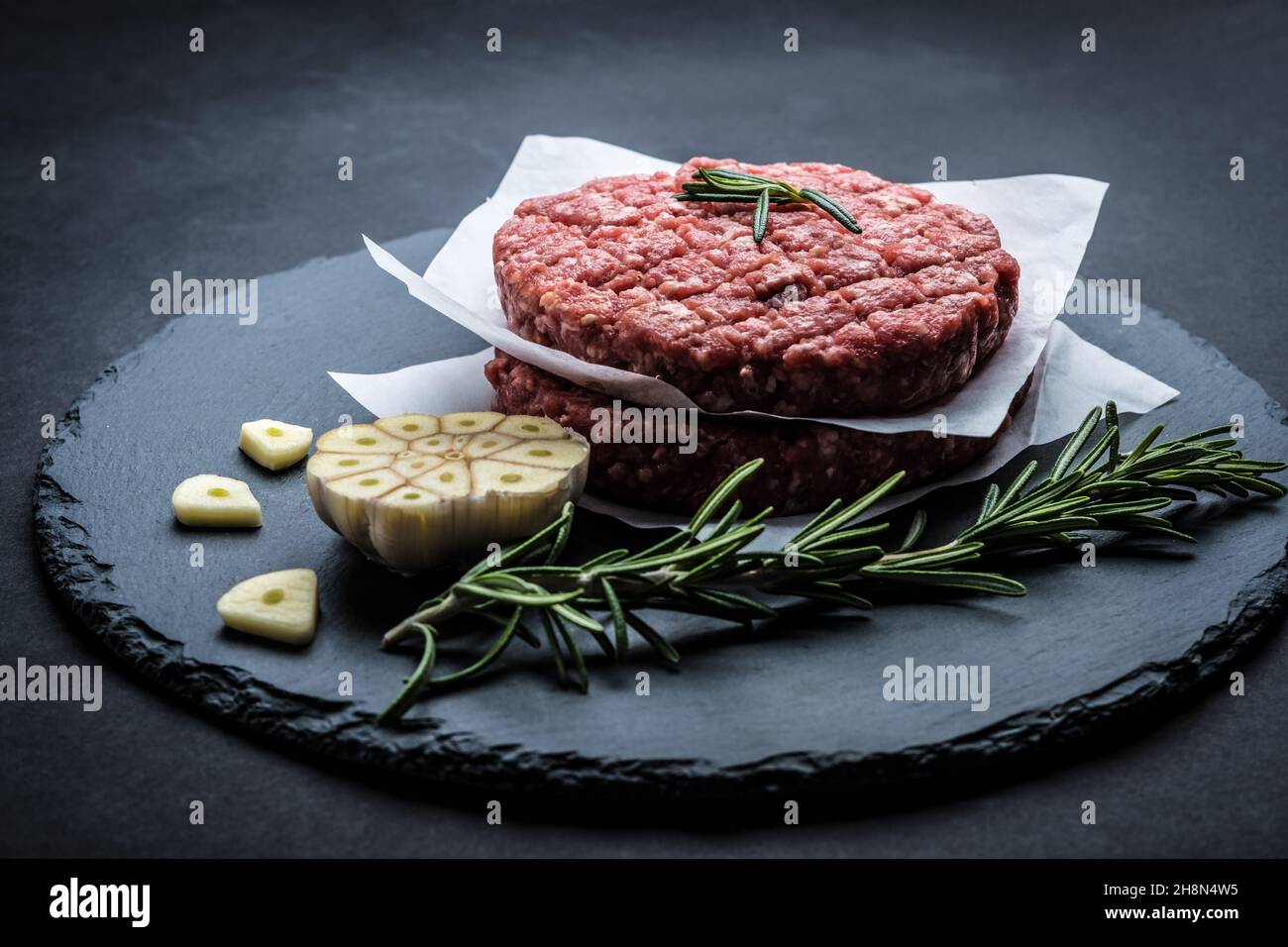 Raw burger beef patty on stone background Stock Photo