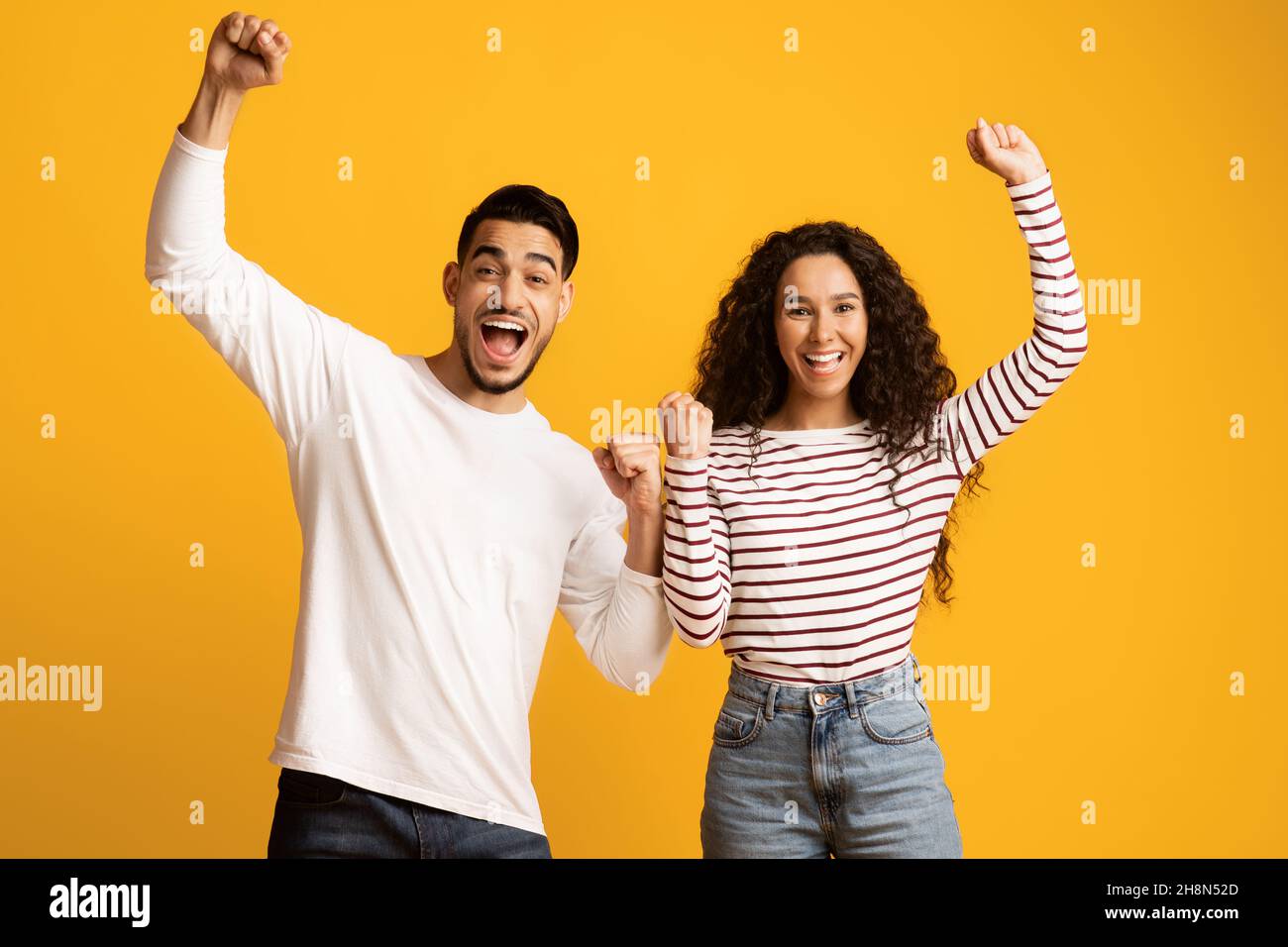 Lucky Winners. Cheerful Excited Middle Eastern Couple Celebrating Success With Raised Fists Stock Photo