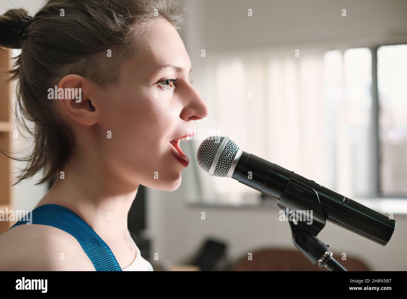 young emotional woman singing into a microphone. female rock singer on ...