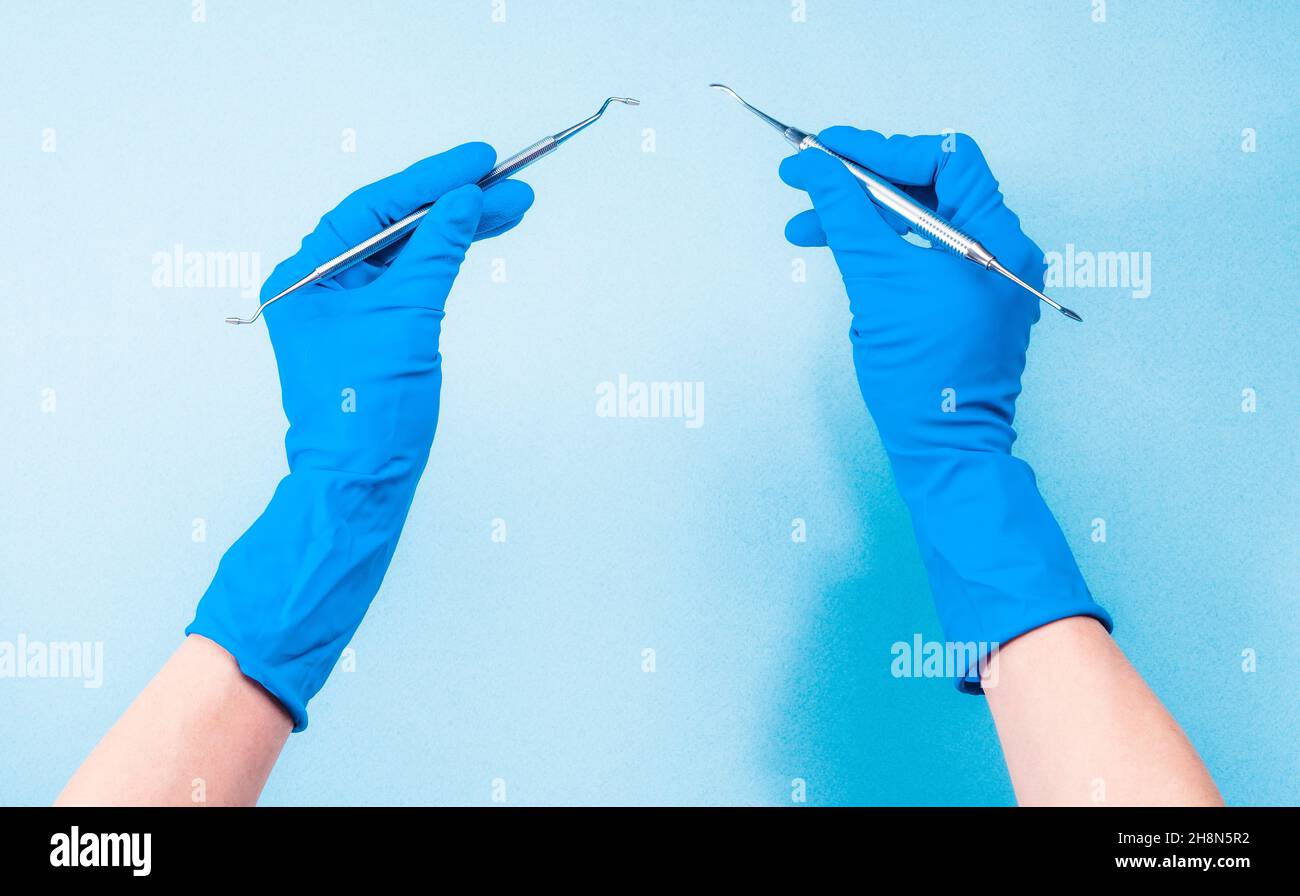 Hands in blue gloves holding dental tools Stock Photo