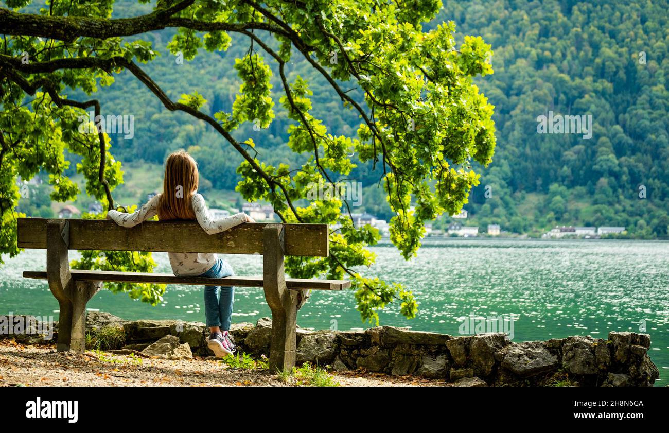 Little girl sitting on the bench and looking on the river scenery Stock ...
