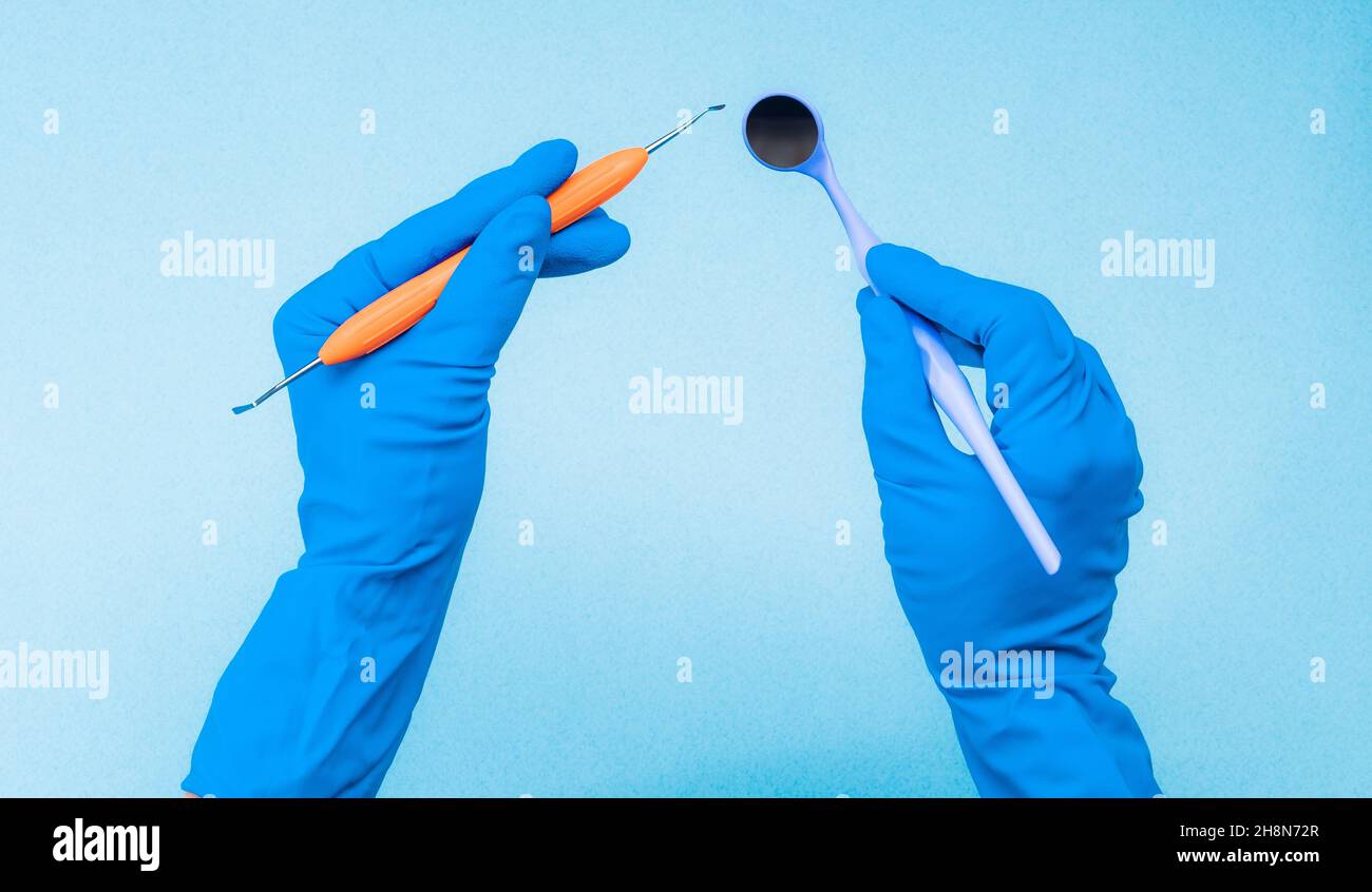 Hands in blue gloves holding dental instruments Stock Photo