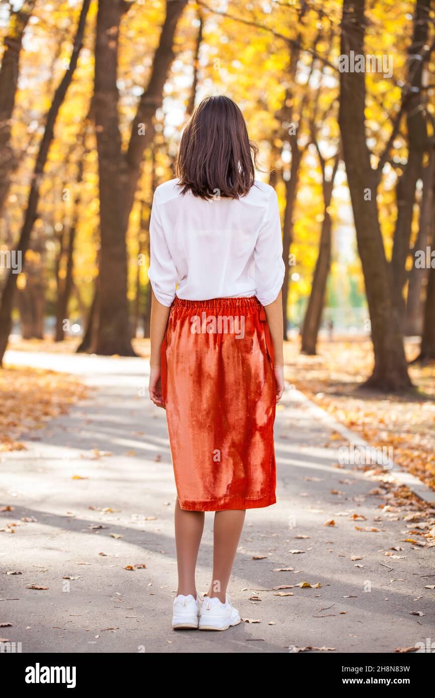 hair model. Back view girl in orange skirt, autumn park
