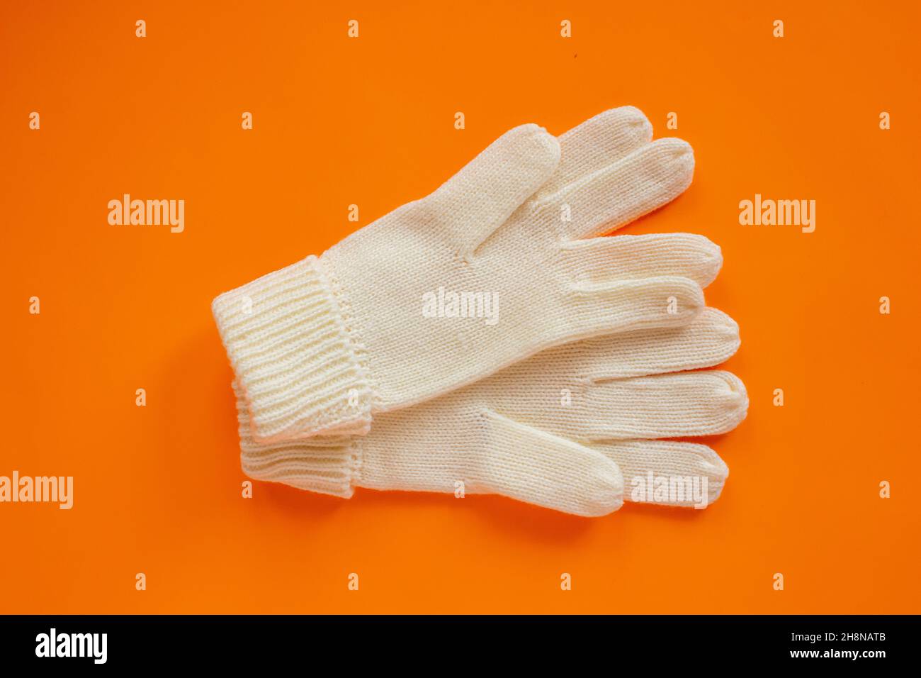 Beige wool gloves, pair of beige gloves isolated on orange background. Stock Photo