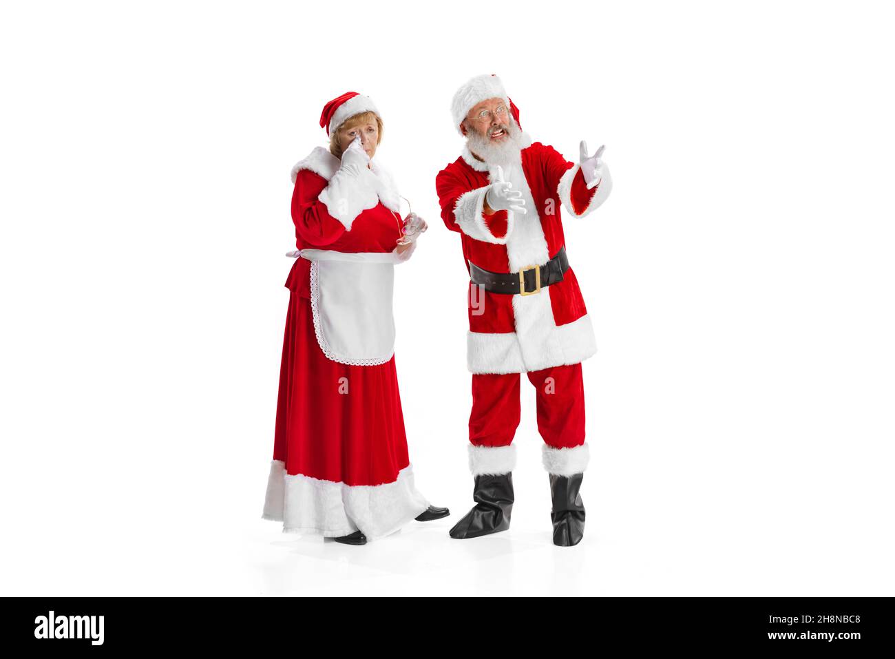 Portrait of two people, man in Santa Claus costume and crying woman, missis Claus isolated on white background. Stock Photo