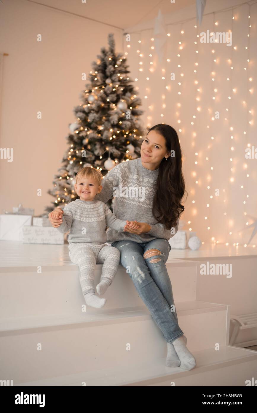 Cheerful Asian Mom And Her Cute Daughter Girl Exchanging Gifts Besides  Window. Parent And Little Child Having Fun Near Christmas Tree Indoors.  Morning Xmas. Portrait Family Close Up. Stock Photo, Picture and