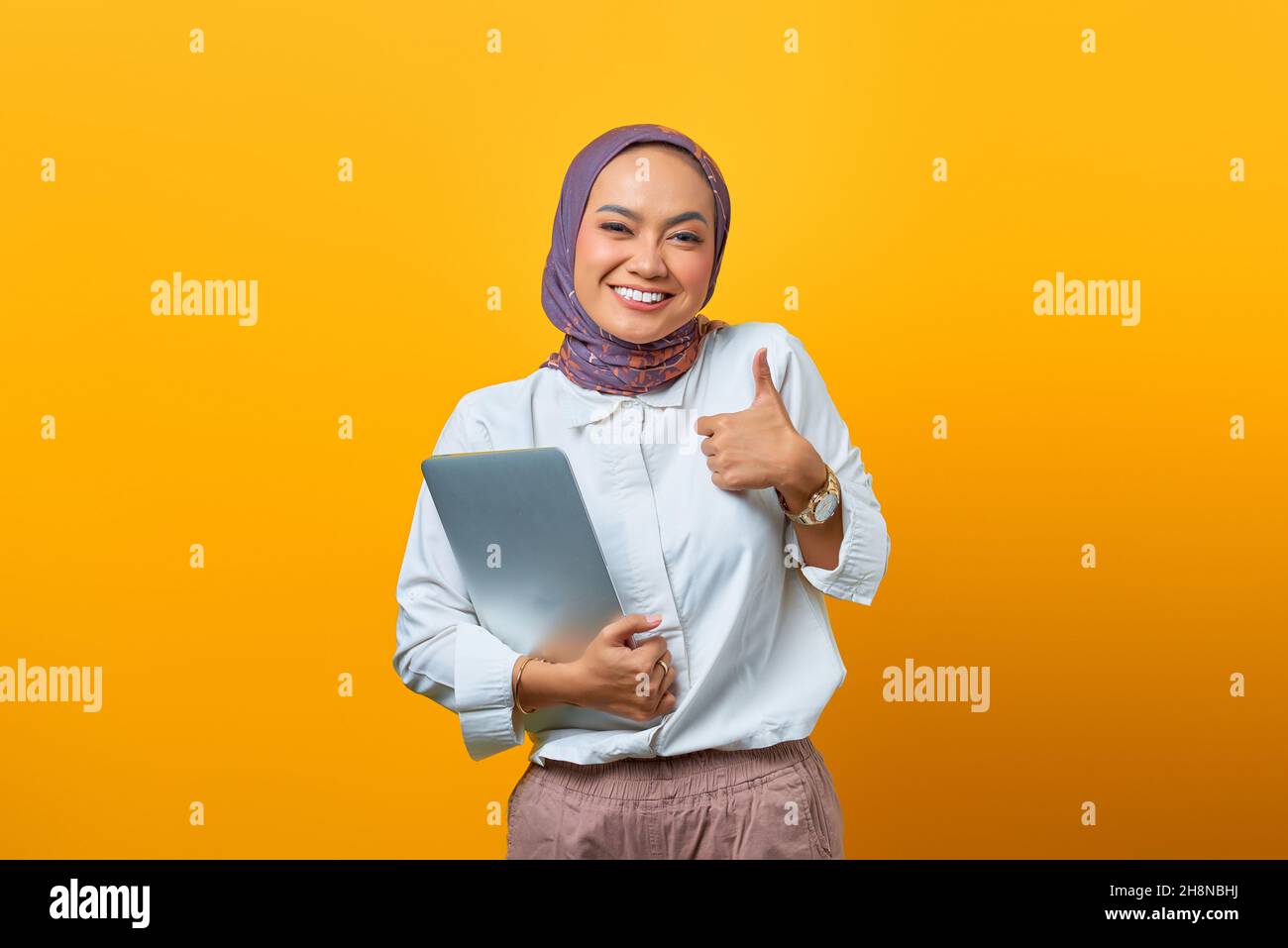 Beautiful Asian woman holding laptop smiling and showing thumbs up sign ...