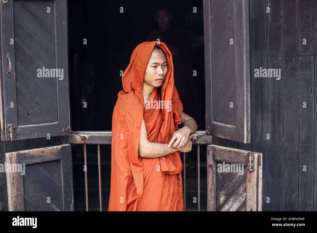 Buddhist monk in orange Kasaya robe, Kesa, Bagaya teak monastery in Inwa, Mandalay region, Myanmar monks buddhism picture image photo Stock Photo
