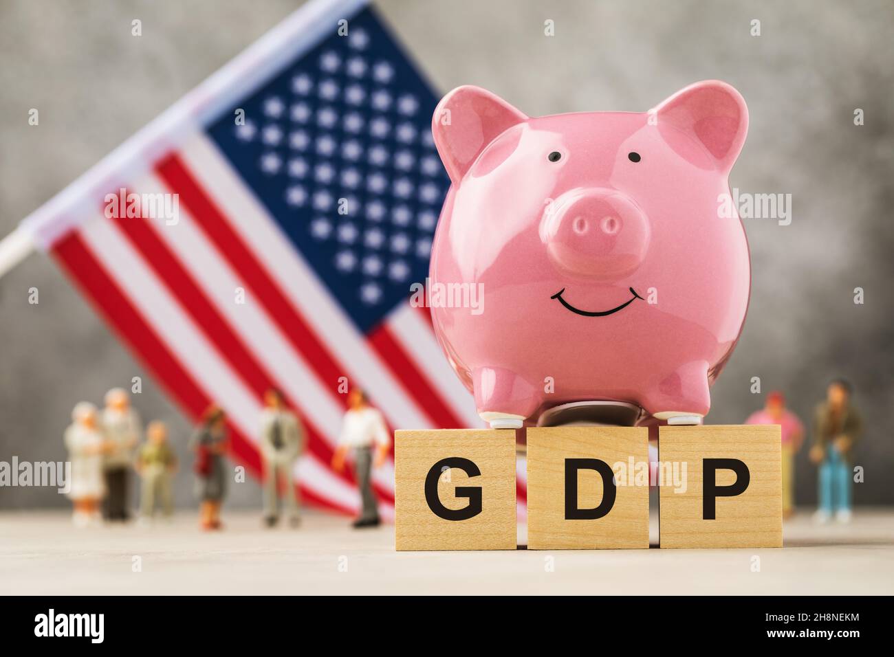 Piggy bank, wooden cubes with text, American flag and plastic toy men on an abstract background, concept on the theme of USA GDP Stock Photo