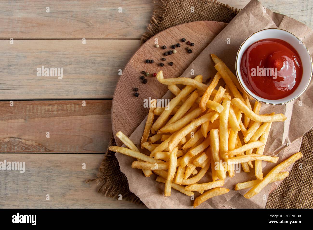 Hot golden french fries with ketchup on wooden background. Tasty american fast food. Place for text Stock Photo