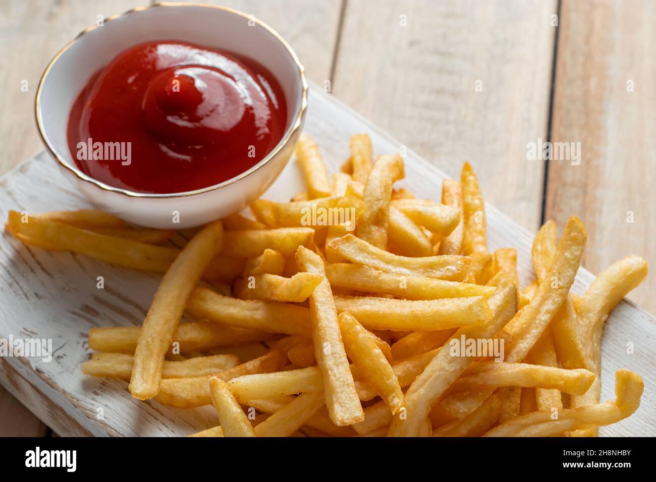 Hot golden french fries with ketchup on wooden background. Tasty american fast food. Place for text Stock Photo