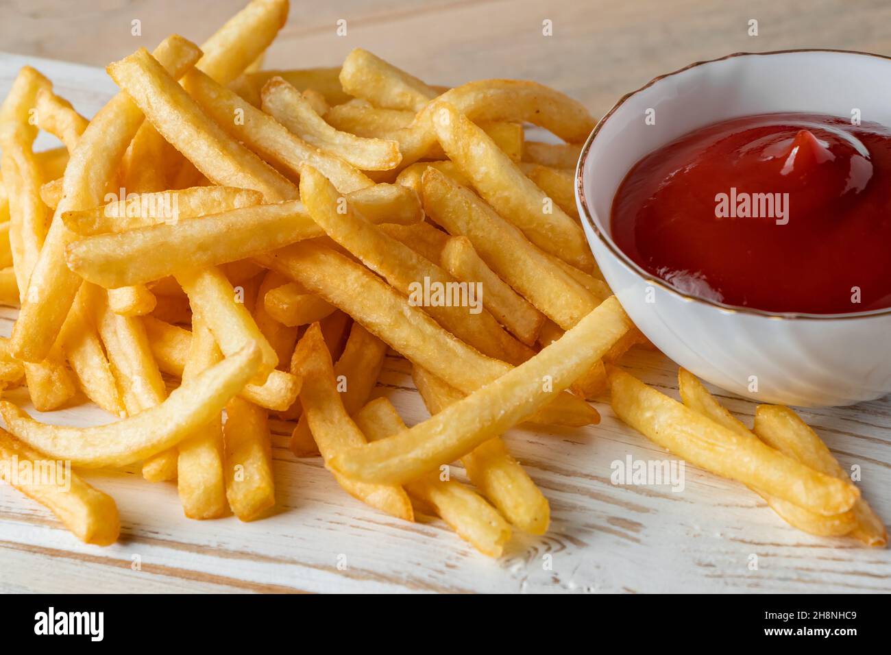 Hot golden french fries with sauce on a wooden background. Homemade rustic food. Stock Photo