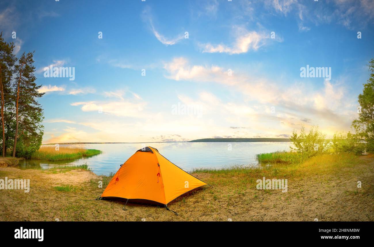 Orange tourist tent on river bank on sunny day Stock Photo