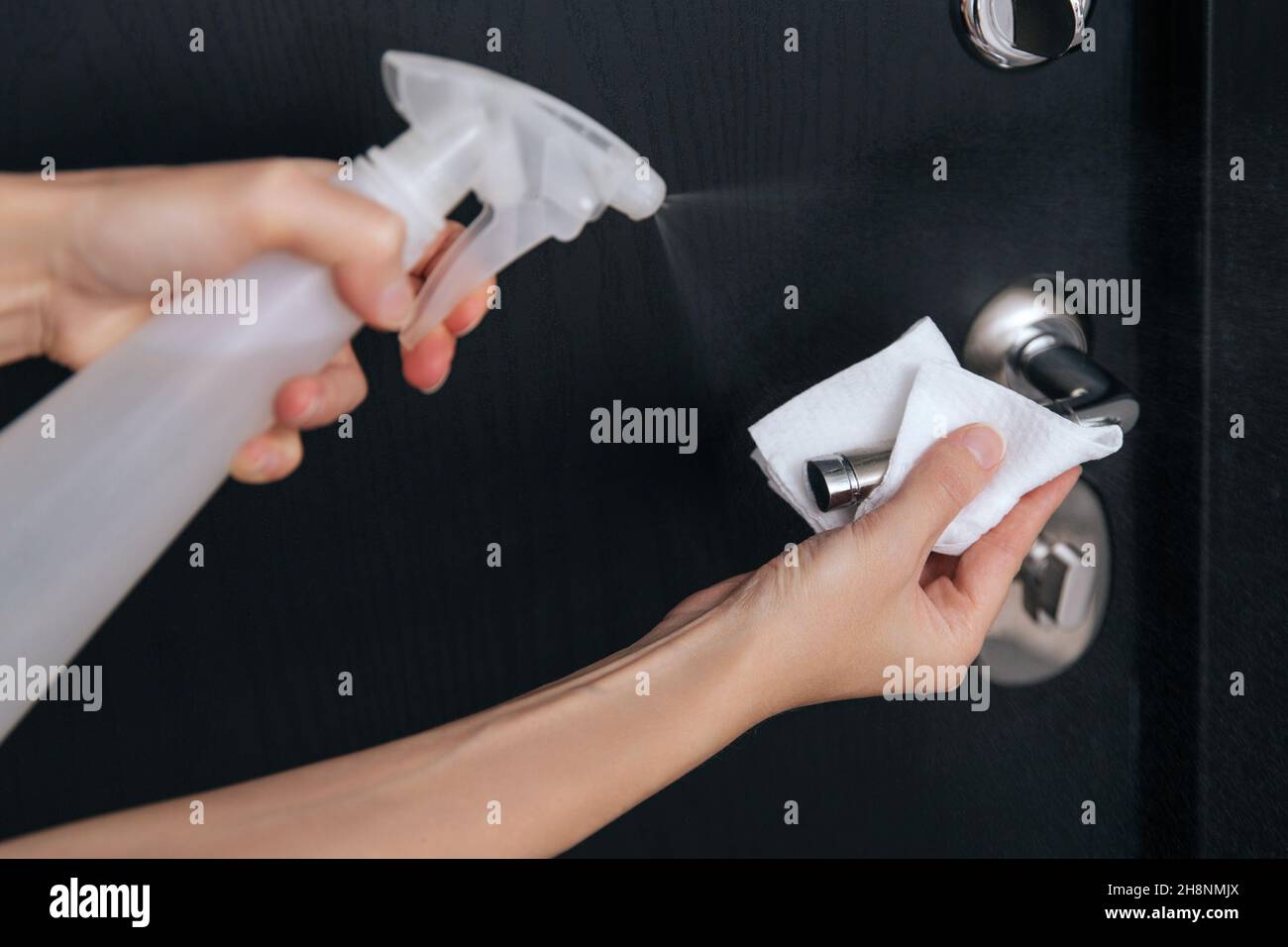 Cleaning black door handles with an antiseptic wet wipe. Woman hand