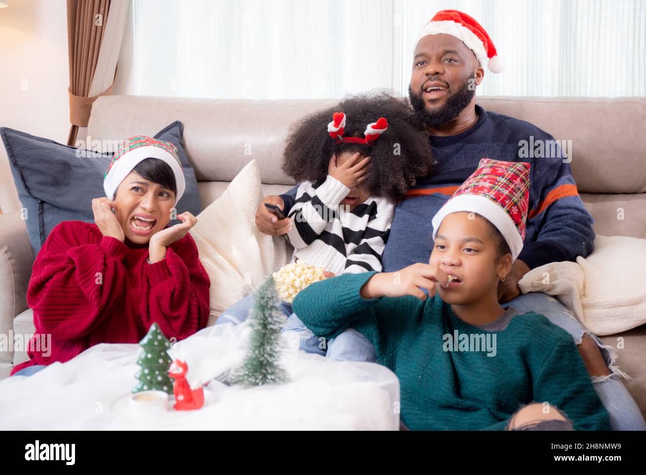 Happy African family sitting on couch watching TV with horror movie in ...