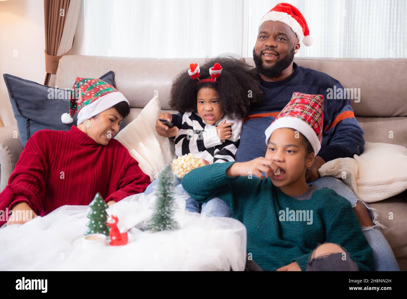 Happy African family sitting on couch watching TV with horror movie in ...
